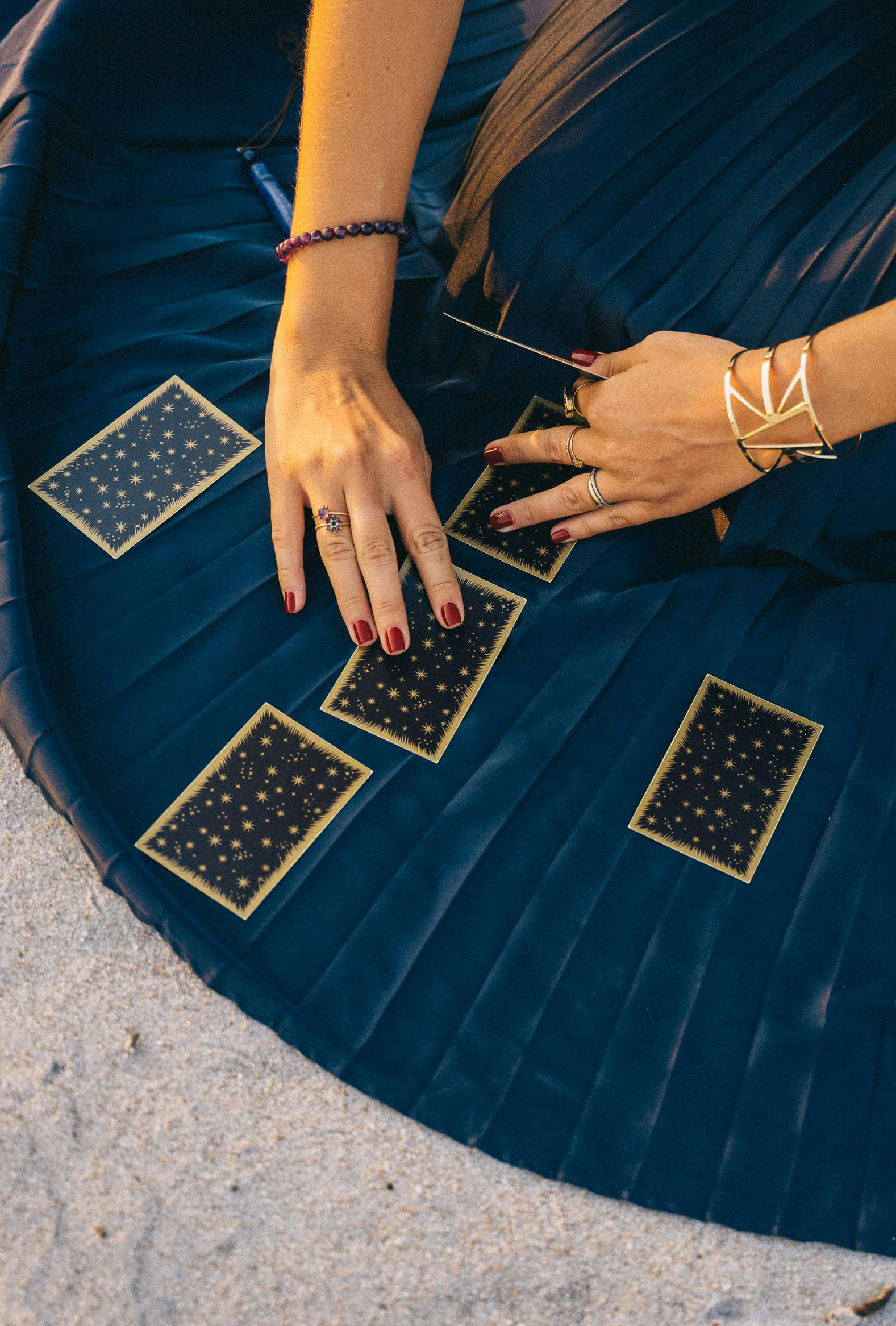 Mains de femme tirant les cartes d'un oracle sur sa robe bleue canard